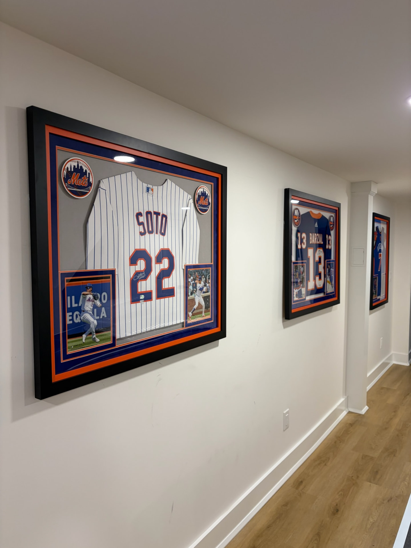 Framed sports jerseys mounted in a row along a hallway wall.